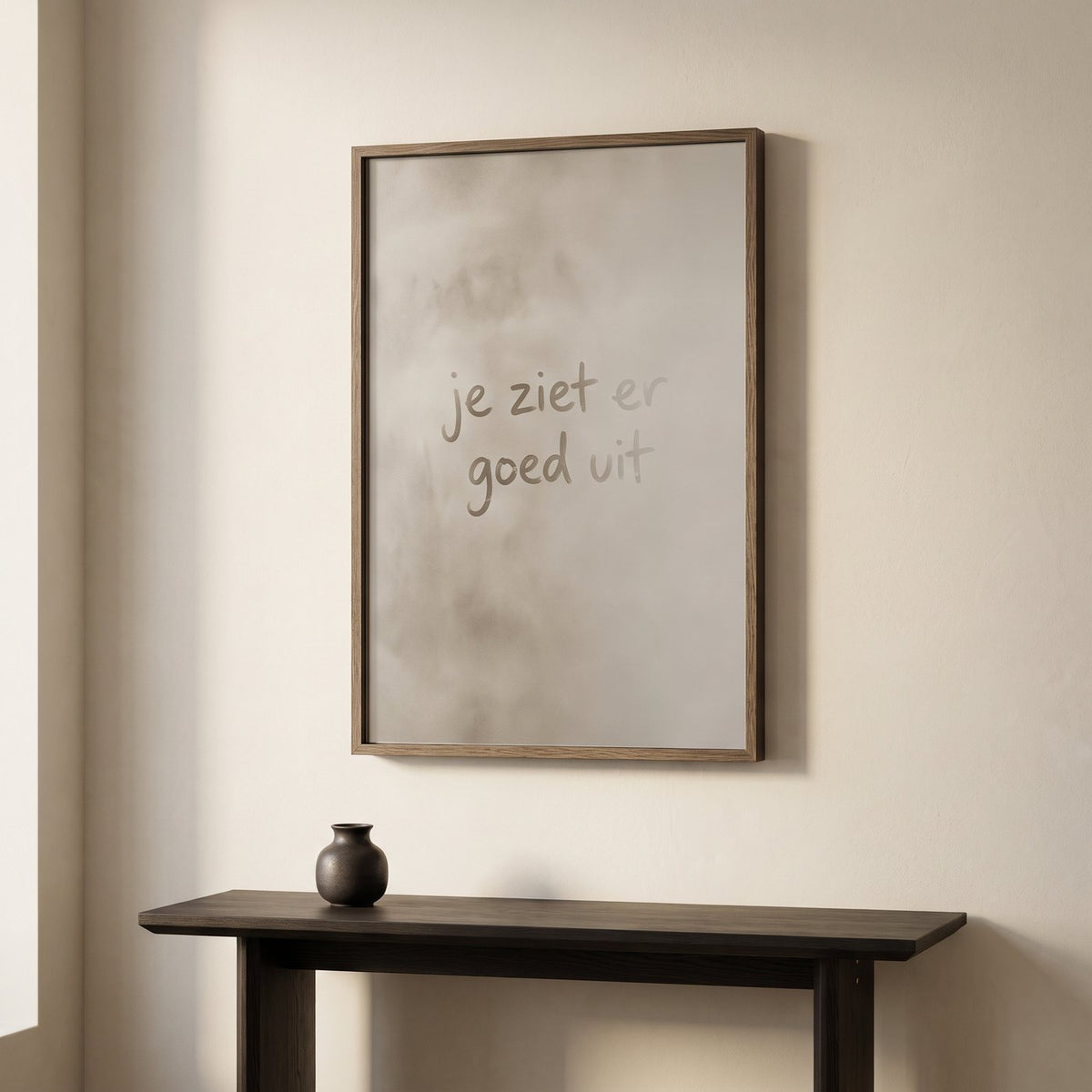 Spiegel in een lijst van gerookt eiken met een matte condenswaas en de tekst 'je ziet er goed uit' in helder spiegelvlak, boven een donkere console